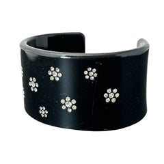 A vintage black plastic cuff bracelet featuring a sleek design with clear rhinestones arranged in small floral patterns. The bracelet, likely from the 2000s, is shown in very good condition with minimal surface scratching, adding timeless elegance and eco-conscious charm to any outfit.