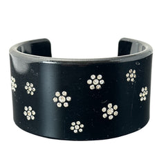 A vintage black plastic cuff bracelet featuring a sleek design with clear rhinestones arranged in small floral patterns. The bracelet, likely from the 2000s, is shown in very good condition with minimal surface scratching, adding timeless elegance and eco-conscious charm to any outfit.