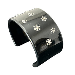 A vintage black plastic cuff bracelet featuring a sleek design with clear rhinestones arranged in small floral patterns. The bracelet, likely from the 2000s, is shown in very good condition with minimal surface scratching, adding timeless elegance and eco-conscious charm to any outfit.