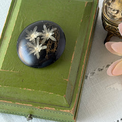 Vintage round brooch with real dried flowers encased in clear resin on a lacquered wood base, shown from multiple angles.