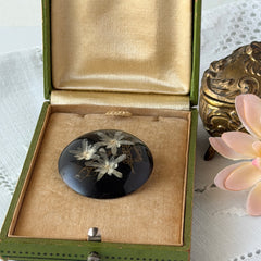 Vintage round brooch with real dried flowers encased in clear resin on a lacquered wood base, shown from multiple angles.