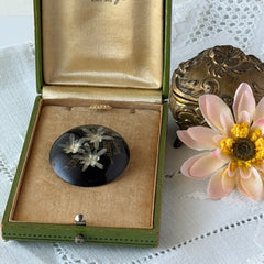 Vintage round brooch with real dried flowers encased in clear resin on a lacquered wood base, shown from multiple angles.