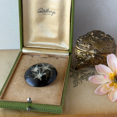 Vintage round brooch with real dried flowers encased in clear resin on a lacquered wood base, shown from multiple angles.