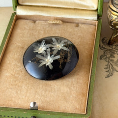 Vintage round brooch with real dried flowers encased in clear resin on a lacquered wood base, shown from multiple angles.