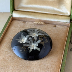Vintage round brooch with real dried flowers encased in clear resin on a lacquered wood base, shown from multiple angles.
