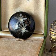 Vintage round brooch with real dried flowers encased in clear resin on a lacquered wood base, shown from multiple angles.
