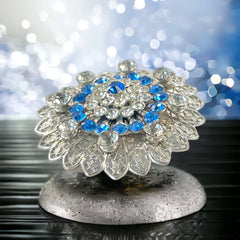 Vintage silver‑tone filigree brooch with sapphire blue and clear rhinestones in a floral design.