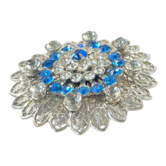 Vintage silver‑tone filigree brooch with sapphire blue and clear rhinestones in a floral design.