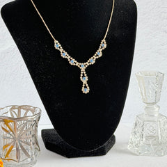 Vintage silver‑tone necklace with a delicate blue and clear rhinestone drop pendant on an adjustable chain.