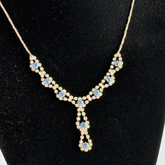 Vintage silver‑tone necklace with a delicate blue and clear rhinestone drop pendant on an adjustable chain.