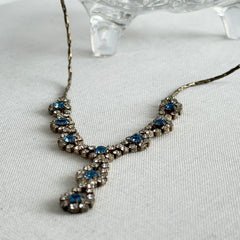 Vintage silver‑tone necklace with a delicate blue and clear rhinestone drop pendant on an adjustable chain.