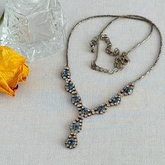 Vintage silver‑tone necklace with a delicate blue and clear rhinestone drop pendant on an adjustable chain.