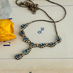Vintage silver‑tone necklace with a delicate blue and clear rhinestone drop pendant on an adjustable chain.