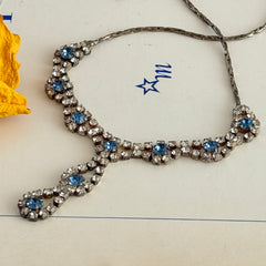 Vintage silver‑tone necklace with a delicate blue and clear rhinestone drop pendant on an adjustable chain.