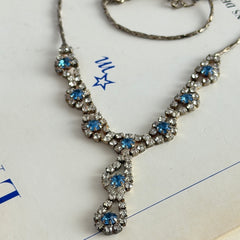 Vintage silver‑tone necklace with a delicate blue and clear rhinestone drop pendant on an adjustable chain.