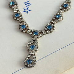 Vintage silver‑tone necklace with a delicate blue and clear rhinestone drop pendant on an adjustable chain.