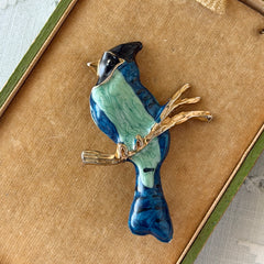 Vintage blue and green enamel gold‑tone bird brooch perched on a branch, shown from multiple angles.
