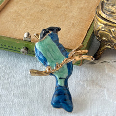 Vintage blue and green enamel gold‑tone bird brooch perched on a branch, shown from multiple angles.