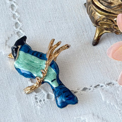 Vintage blue and green enamel gold‑tone bird brooch perched on a branch, shown from multiple angles.