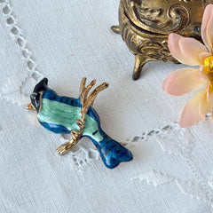 Vintage blue and green enamel gold‑tone bird brooch perched on a branch, shown from multiple angles.