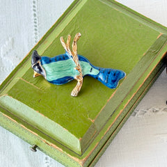 Vintage blue and green enamel gold‑tone bird brooch perched on a branch, shown from multiple angles.