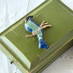 Vintage blue and green enamel gold‑tone bird brooch perched on a branch, shown from multiple angles.