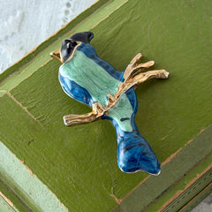 Vintage blue and green enamel gold‑tone bird brooch perched on a branch, shown from multiple angles.