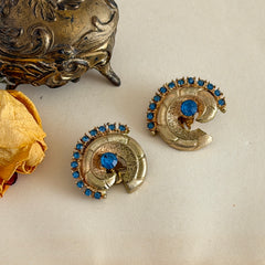 Vintage 1980s textured gold tone spiral clip-on earrings with blue rhinestones.