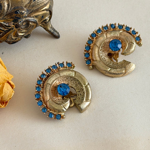 Vintage 1980s textured gold tone spiral clip-on earrings with blue rhinestones.