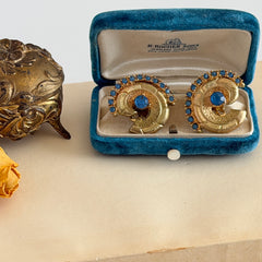 Vintage 1980s textured gold tone spiral clip-on earrings with blue rhinestones.