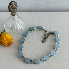 Vintage 1950s necklace with baby blue moonglow teardrop thermoset panels set in silver‑tone links, displayed on a light fabric background.