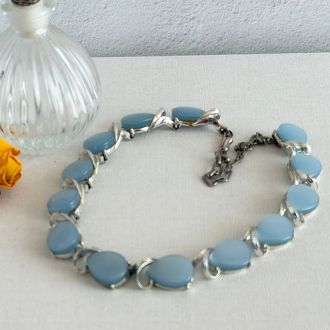 Vintage 1950s necklace with baby blue moonglow teardrop thermoset panels set in silver‑tone links, displayed on a light fabric background.
