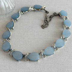 Vintage 1950s necklace with baby blue moonglow teardrop thermoset panels set in silver‑tone links, displayed on a light fabric background.