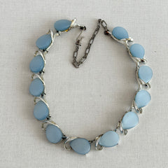 Vintage 1950s necklace with baby blue moonglow teardrop thermoset panels set in silver‑tone links, displayed on a light fabric background.