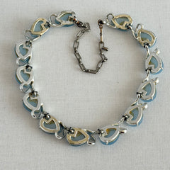 Vintage 1950s necklace with baby blue moonglow teardrop thermoset panels set in silver‑tone links, displayed on a light fabric background.