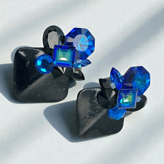 Vintage 1980s statement clip-on earrings with capri blue vitrail and black crystals in geometric cuts, set on a black leather square base.