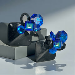 Vintage 1980s statement clip-on earrings with capri blue vitrail and black crystals in geometric cuts, set on a black leather square base.