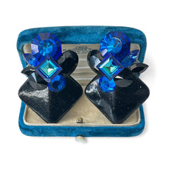 Vintage 1980s statement clip-on earrings with capri blue vitrail and black crystals in geometric cuts, set on a black leather square base.