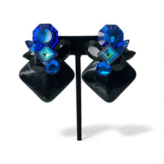 Vintage 1980s statement clip-on earrings with capri blue vitrail and black crystals in geometric cuts, set on a black leather square base.