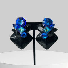 Vintage 1980s statement clip-on earrings with capri blue vitrail and black crystals in geometric cuts, set on a black leather square base.