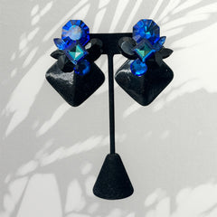 Vintage 1980s statement clip-on earrings with capri blue vitrail and black crystals in geometric cuts, set on a black leather square base.