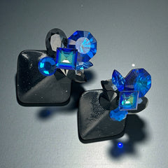 Vintage 1980s statement clip-on earrings with capri blue vitrail and black crystals in geometric cuts, set on a black leather square base.