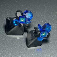 Vintage 1980s statement clip-on earrings with capri blue vitrail and black crystals in geometric cuts, set on a black leather square base.