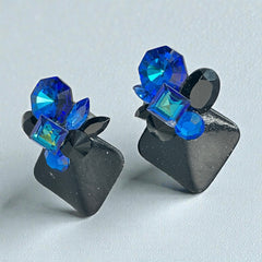 Vintage 1980s statement clip-on earrings with capri blue vitrail and black crystals in geometric cuts, set on a black leather square base.