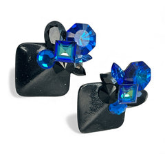 Vintage 1980s statement clip-on earrings with capri blue vitrail and black crystals in geometric cuts, set on a black leather square base.