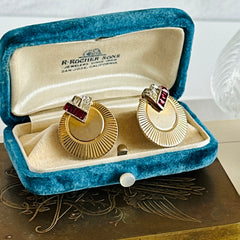 Pair of vintage Marcel Boucher gold‑tone disk clip‑on earrings with ruby‑red baguette rhinestones and clear rhinestone accents.