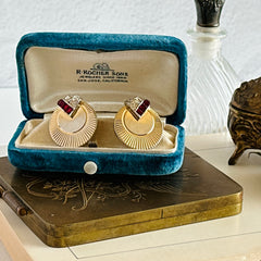 Pair of vintage Marcel Boucher gold‑tone disk clip‑on earrings with ruby‑red baguette rhinestones and clear rhinestone accents.