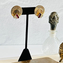 Pair of vintage Marcel Boucher gold‑tone disk clip‑on earrings with ruby‑red baguette rhinestones and clear rhinestone accents.