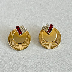 Pair of vintage Marcel Boucher gold‑tone disk clip‑on earrings with ruby‑red baguette rhinestones and clear rhinestone accents.