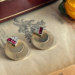 Pair of vintage Marcel Boucher gold‑tone disk clip‑on earrings with ruby‑red baguette rhinestones and clear rhinestone accents.